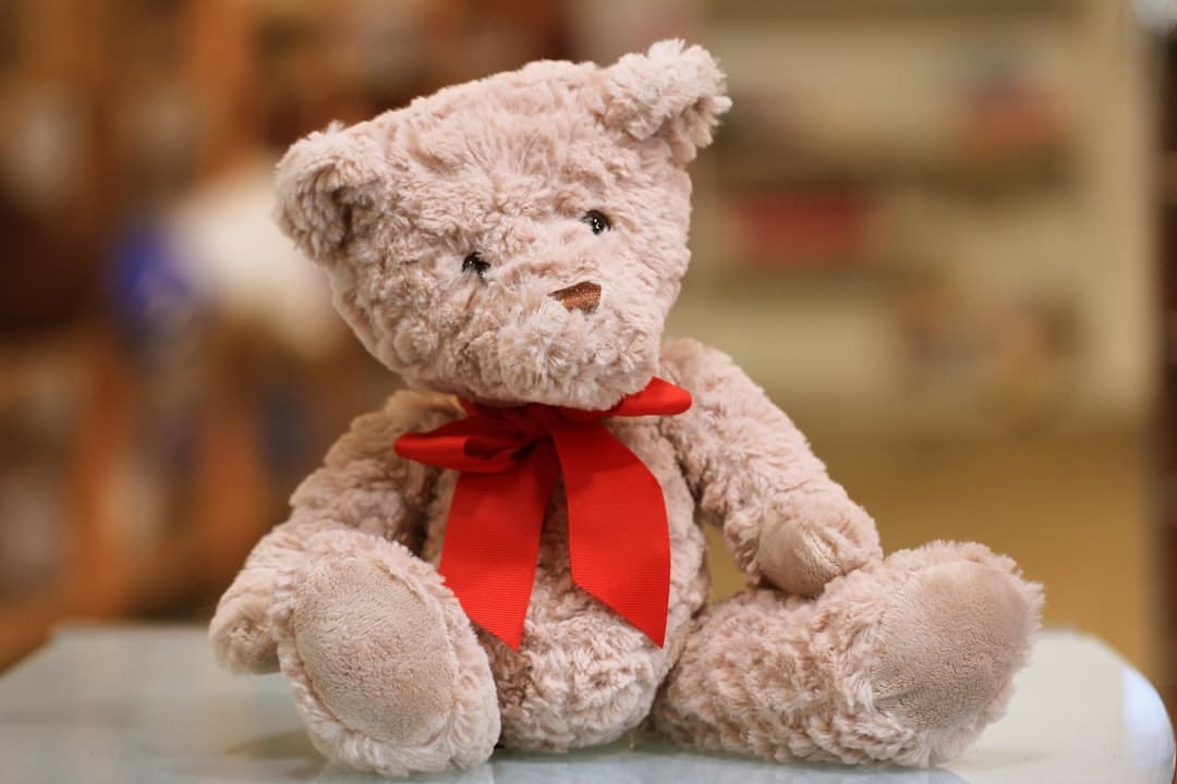 small brown fluffy teddy bear with bow sitting on table